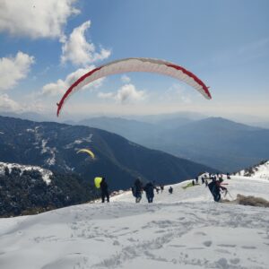 Paragliding in winter with snow-covered peaks and clear blue skies Bir Billing